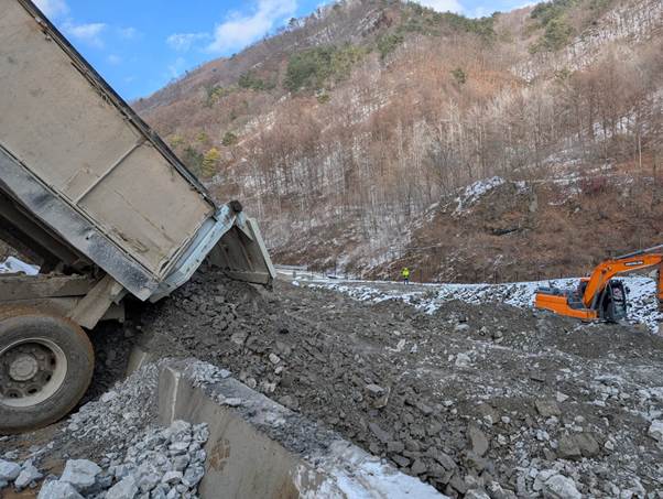 A truck dumping rocks on a road